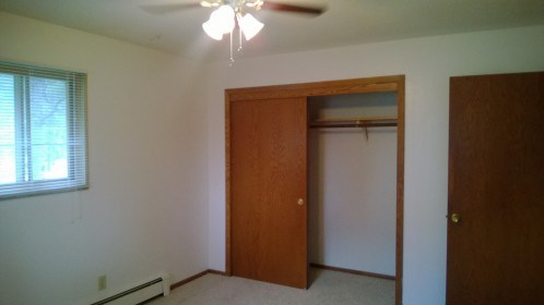 an empty room with a ceiling fan and a closet